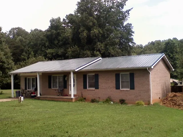 Gray metal roof on a brick ranch house with a side carport in Mcchord Afb