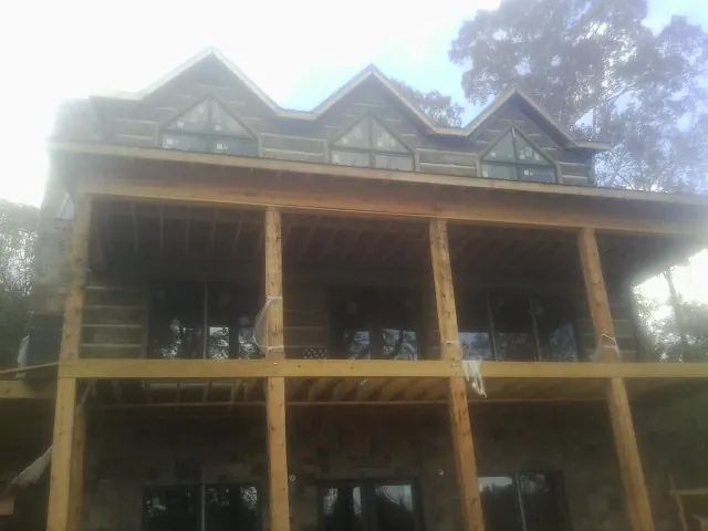Dormers and porch framing on a large log home under construction — Roof Coating work by our crew in Mcchord Afb