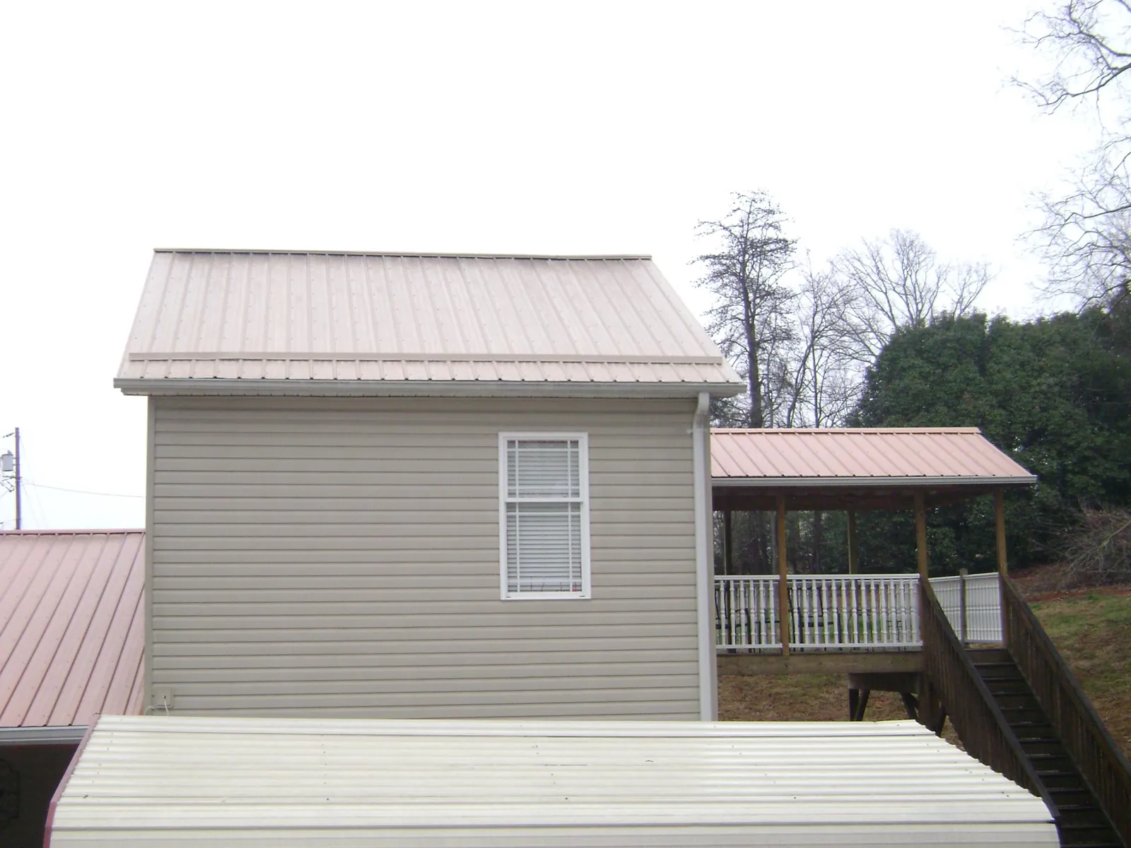 Tan metal roofs on a two story addition and attached porch, from a Roof Replacement job in Mcchord Afb